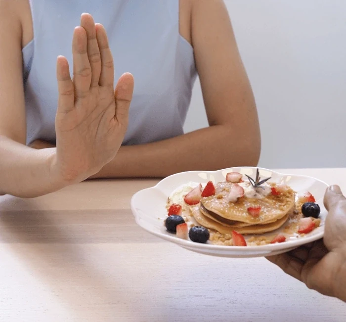 A hand declining a plate at a table